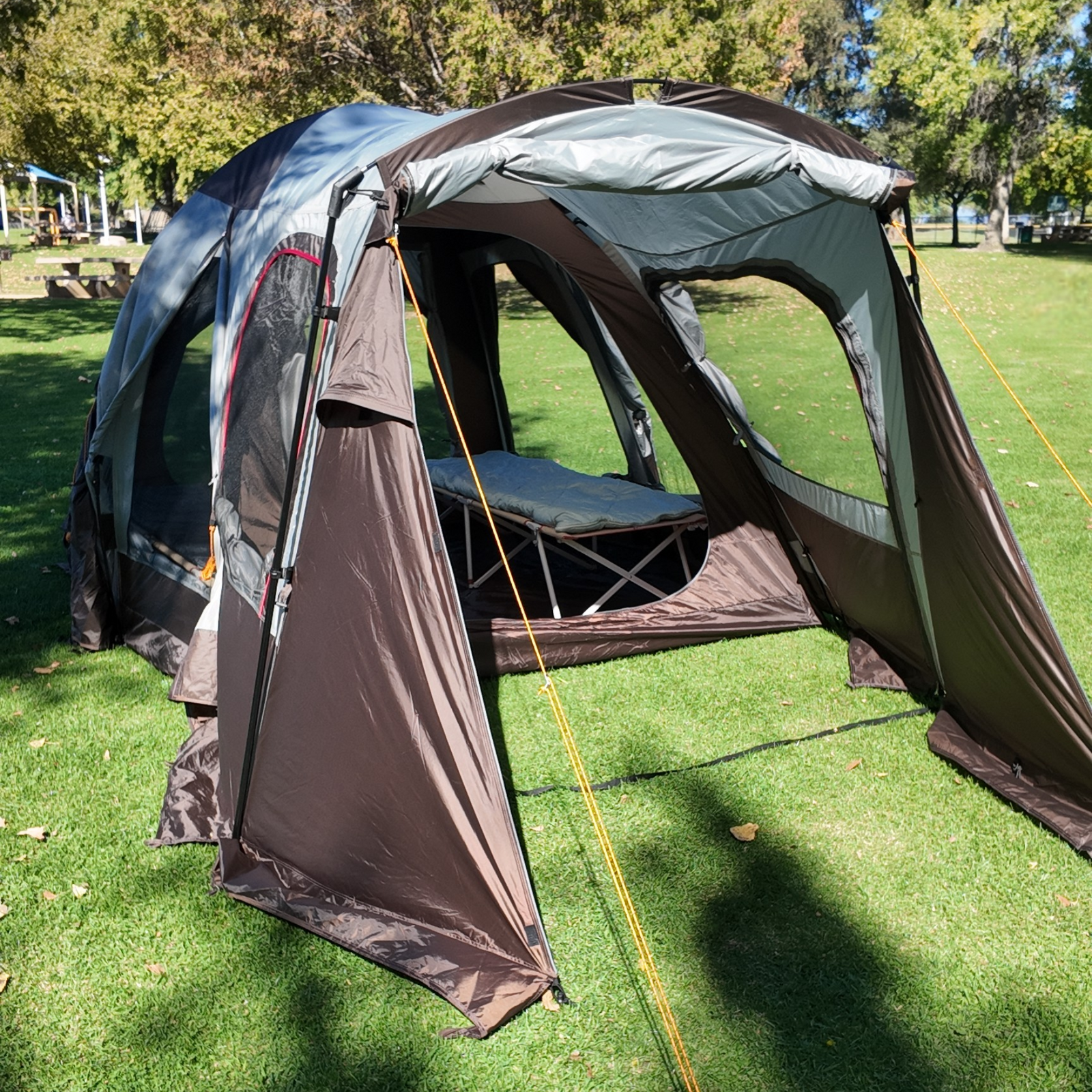 Camping tent with attached porch on a grassy field